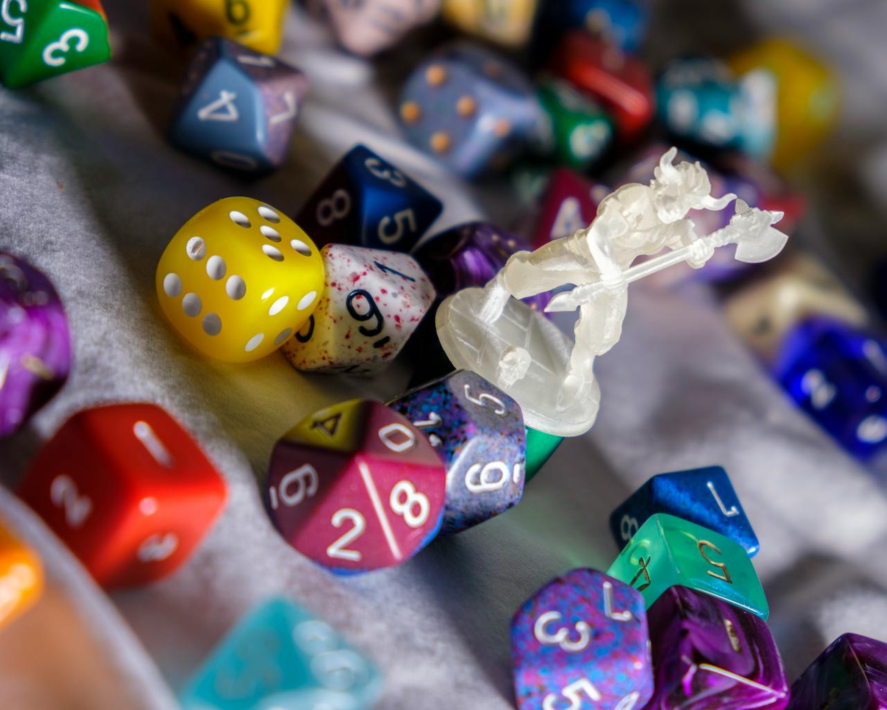 A scattering of various polyhedral dice with a small clear mini of a minotaur holding a battleaxe