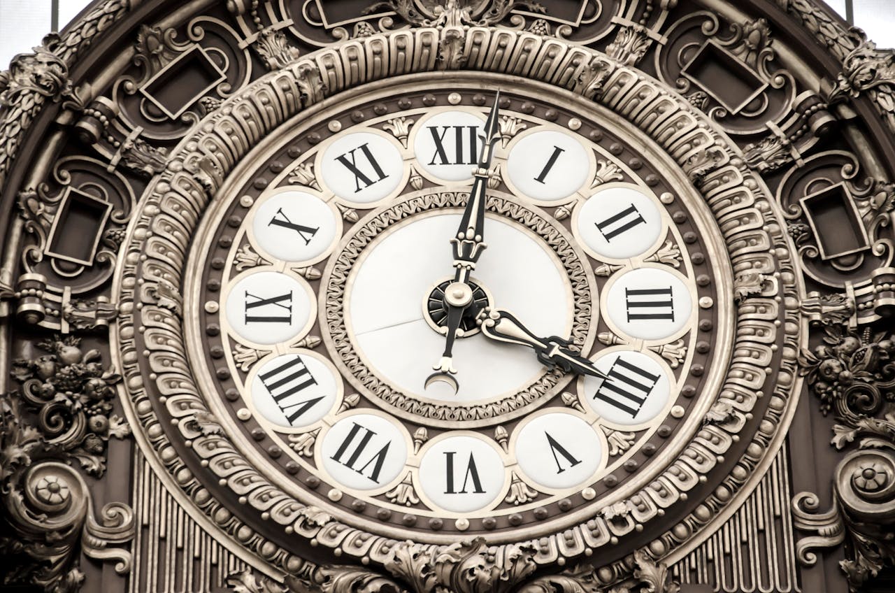 An ornate clockface marked in Roman numerals and surrounded by carvings and designs
