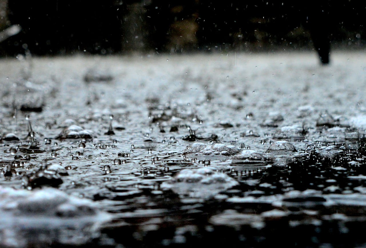 A closeup of raindrops falling on the ground.