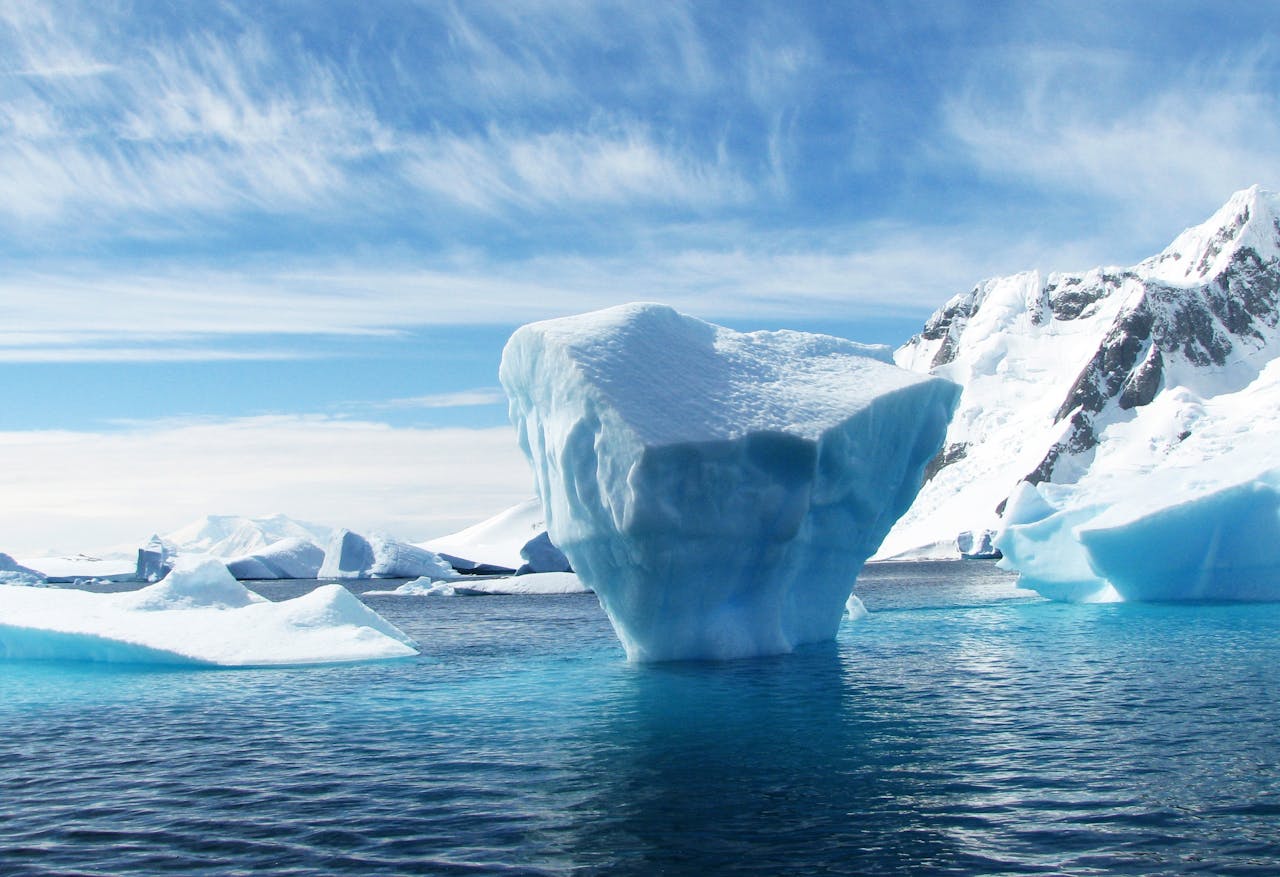 An iceberg in a frozen bay. The image is all blues and whites.